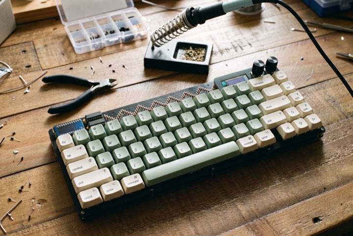 A Lagom with sage green keycaps on a workbench beside a soldering iron